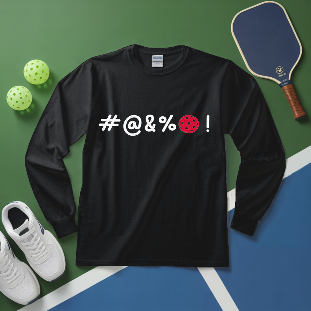 Black long-sleeve shirt with '#@&%' text, pickleball paddle, balls, and shoes on a green and blue surface.