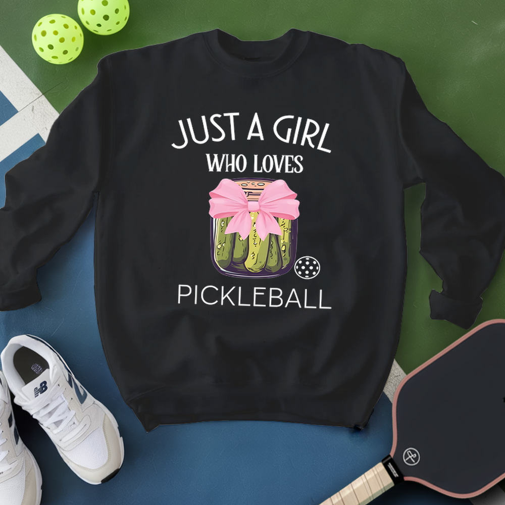 Black sweatshirt with pickleball design and text, surrounded by pickleballs and a paddle on a green and blue background.