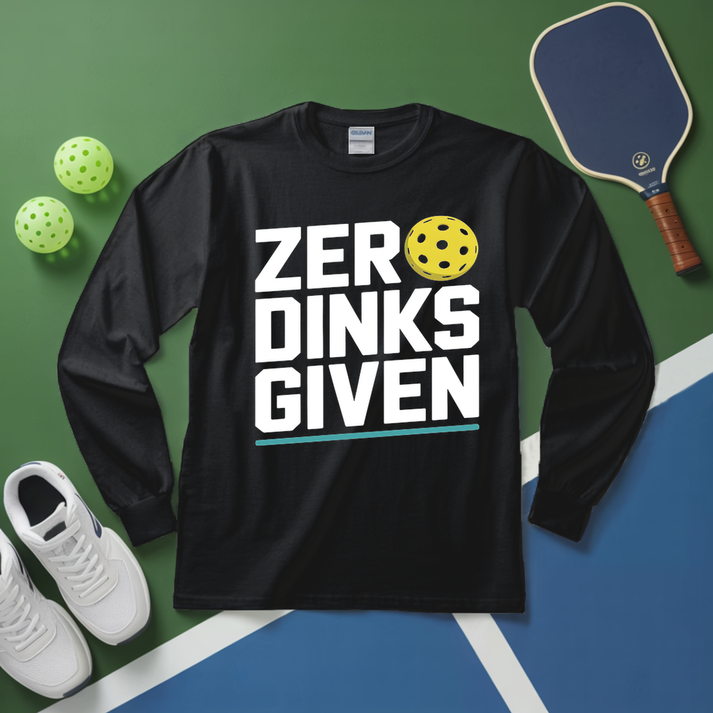Black long-sleeve shirt with 'ZERO DINKS GIVEN' text on a sports court background with pickleball equipment.