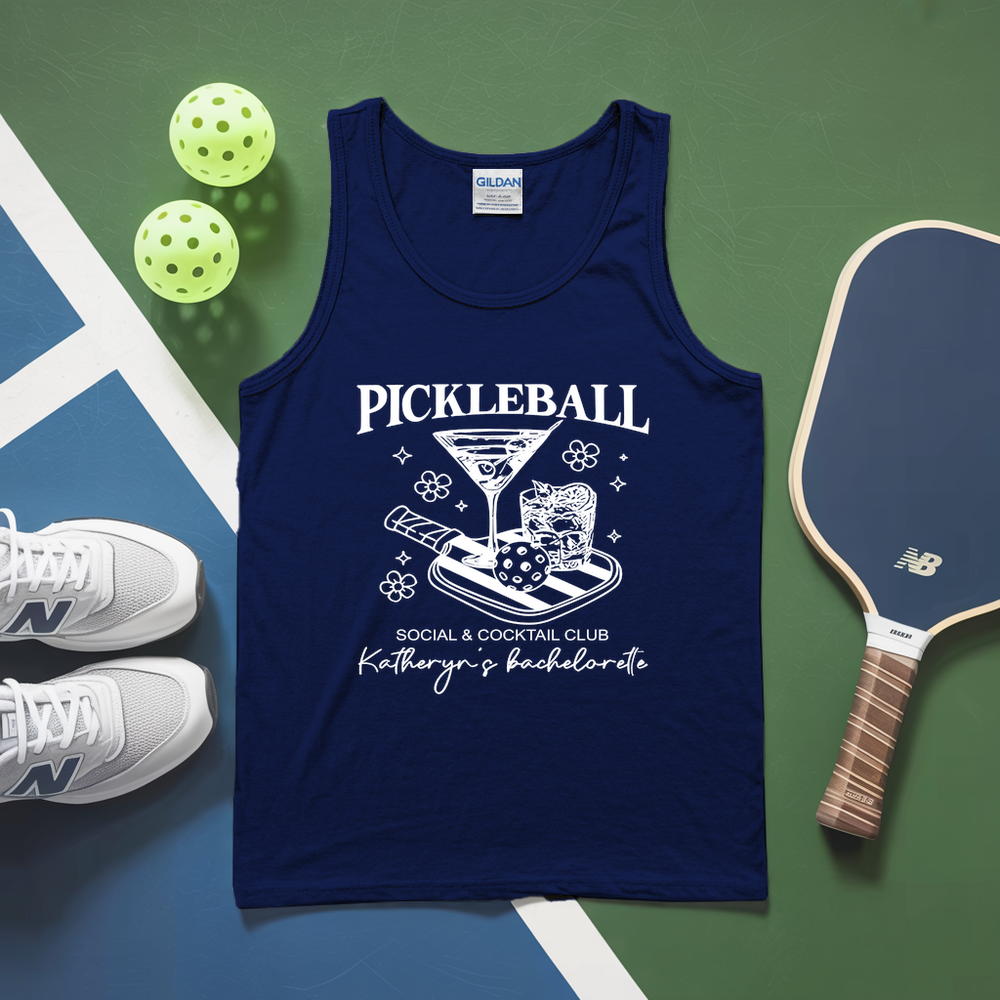 Navy tank top with pickleball design on a green and blue surface with pickleballs and paddle.