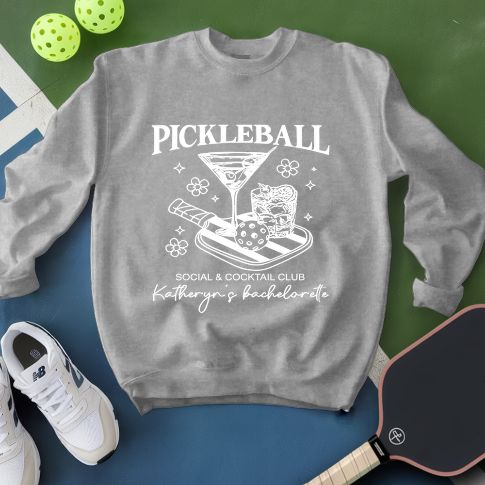 Gray sweatshirt with pickleball-themed design on a green and blue background