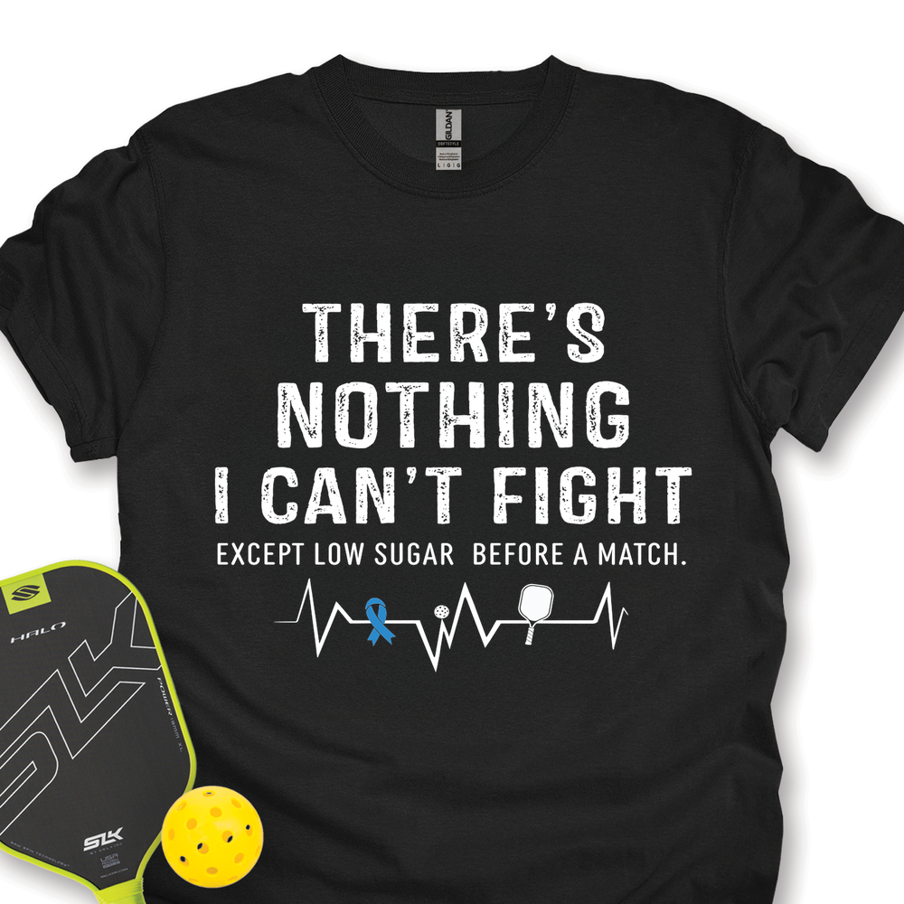 Black t-shirt with motivational quote and pickleball accessories on a white background