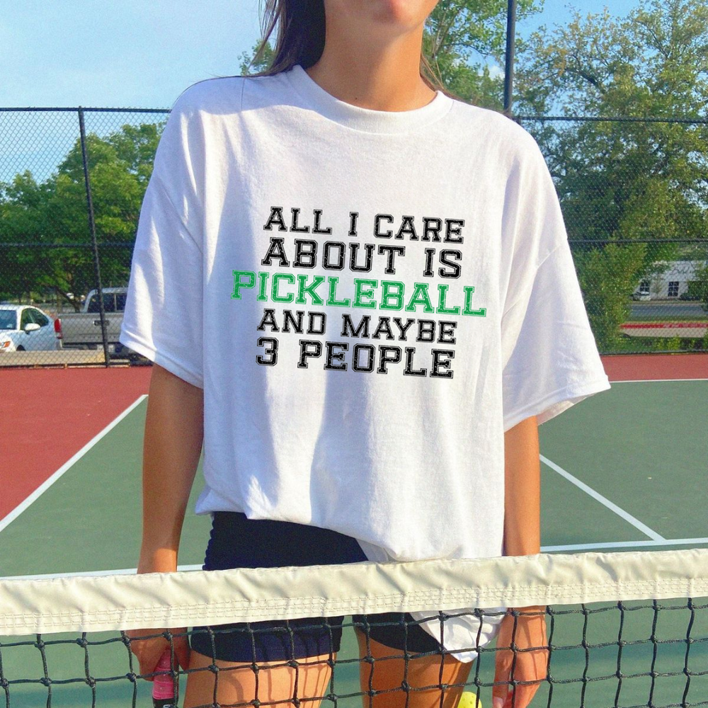 Person wearing a white t-shirt with text on a tennis court