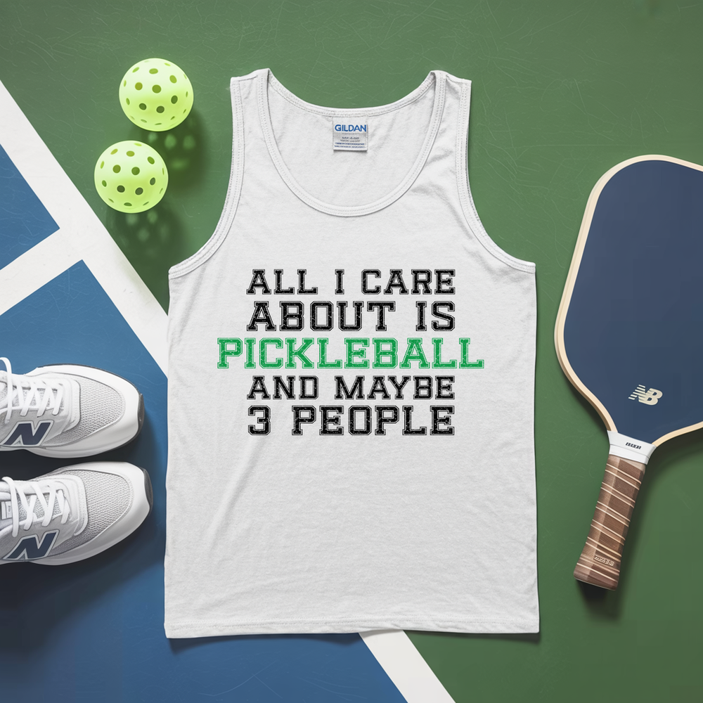 White tank top with pickleball text, pickleballs, and paddle on a green and blue background
