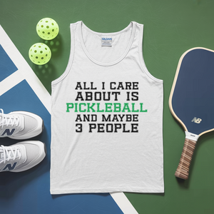 White tank top with pickleball text, pickleballs, and paddle on a green and blue background