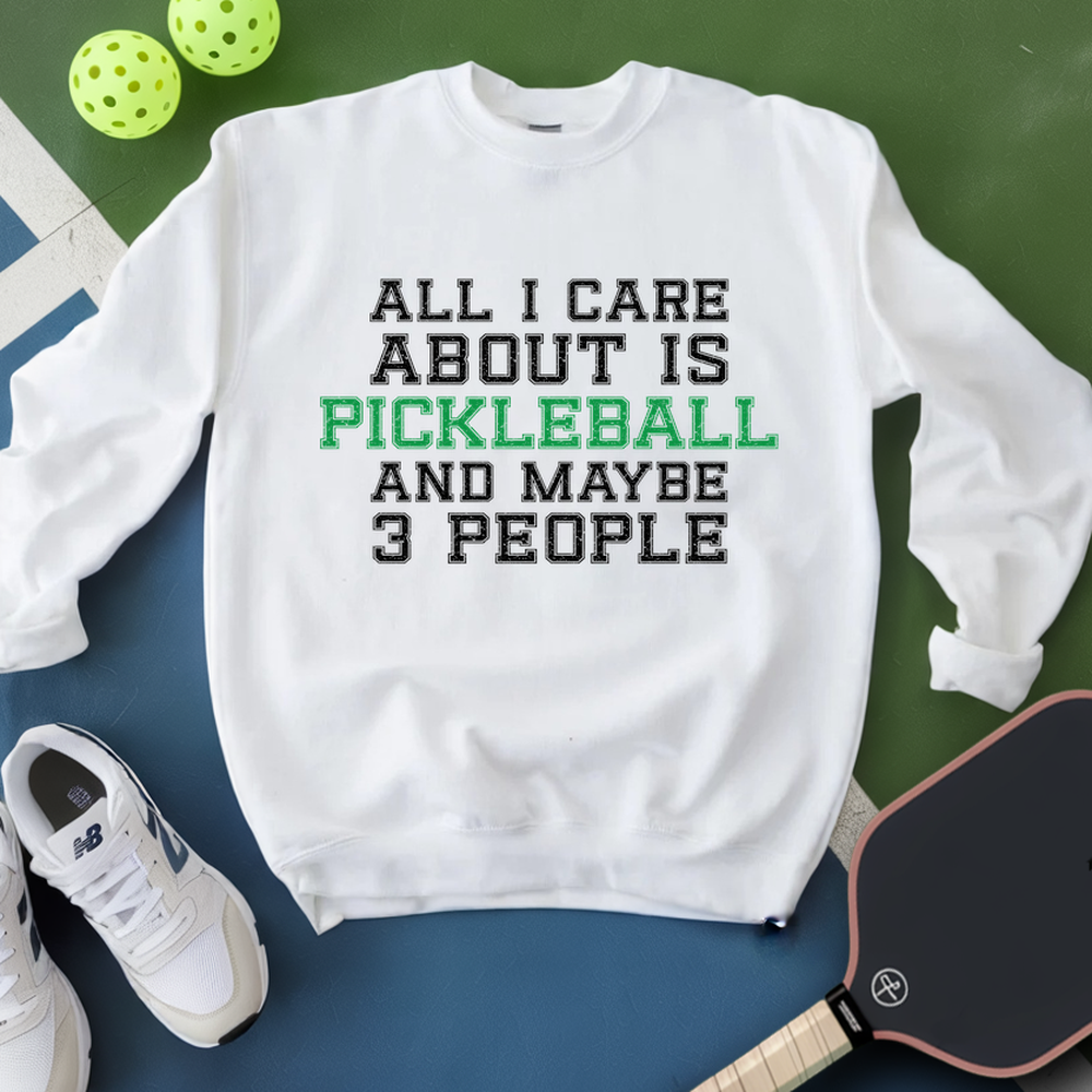 White sweatshirt with text 'All I care about is pickleball and maybe 3 people' on a green and blue background with pickleballs and a paddle.