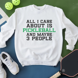 White sweatshirt with text 'All I care about is pickleball and maybe 3 people' on a green and blue background with pickleballs and a paddle.