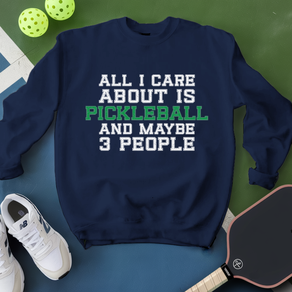 Navy sweatshirt with pickleball text, shoes, and paddle on a green surface