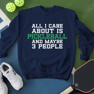 Navy sweatshirt with pickleball text, shoes, and paddle on a green surface
