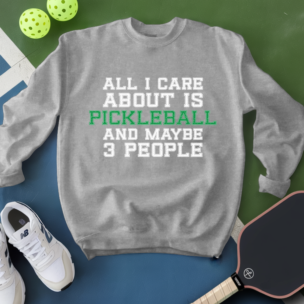 Gray sweatshirt with text 'All I care about is pickleball and maybe 3 people' on a green and blue background with pickleball equipment.