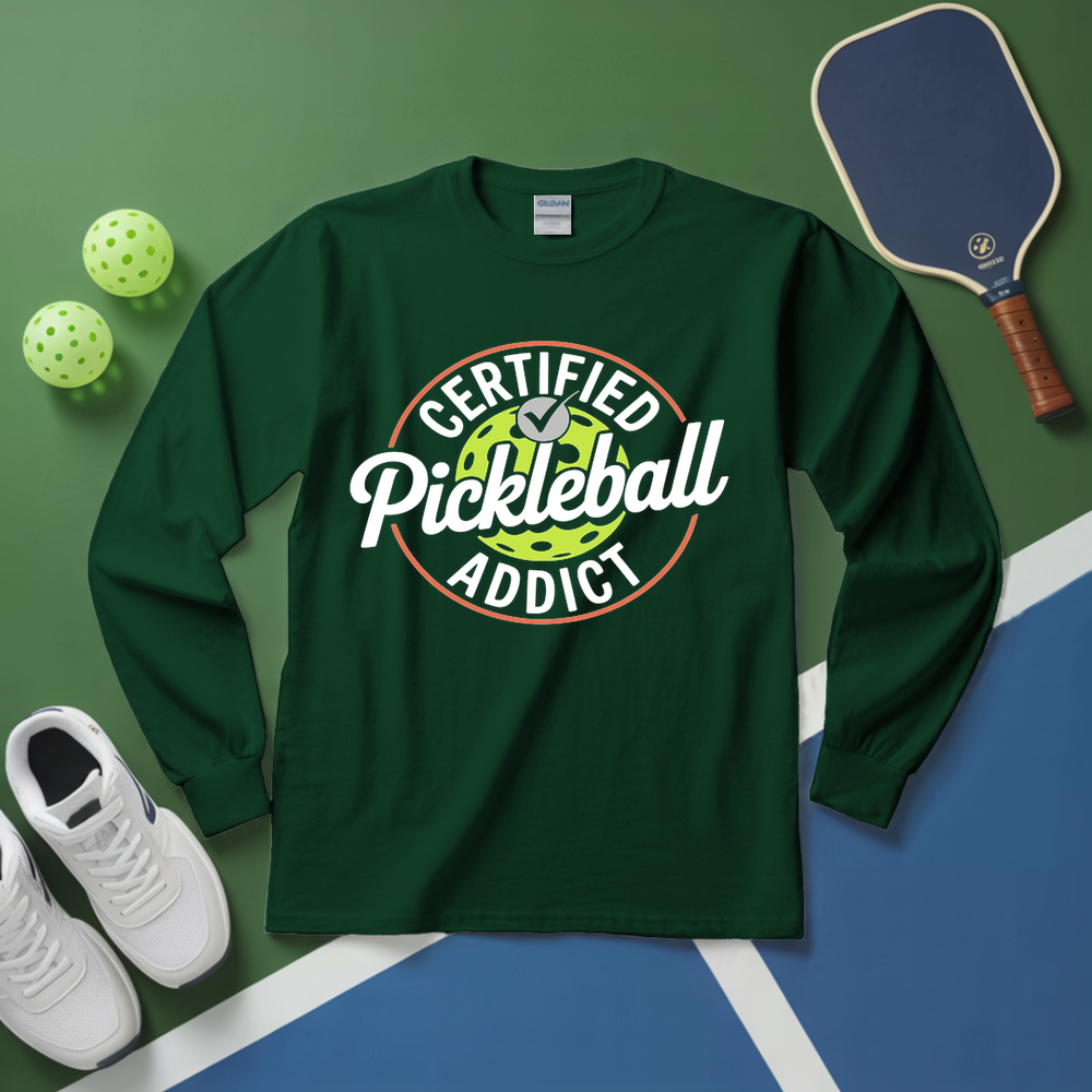 Green long-sleeve shirt with 'Certified Pickleball Addict' design on a green and blue surface with pickleball equipment.