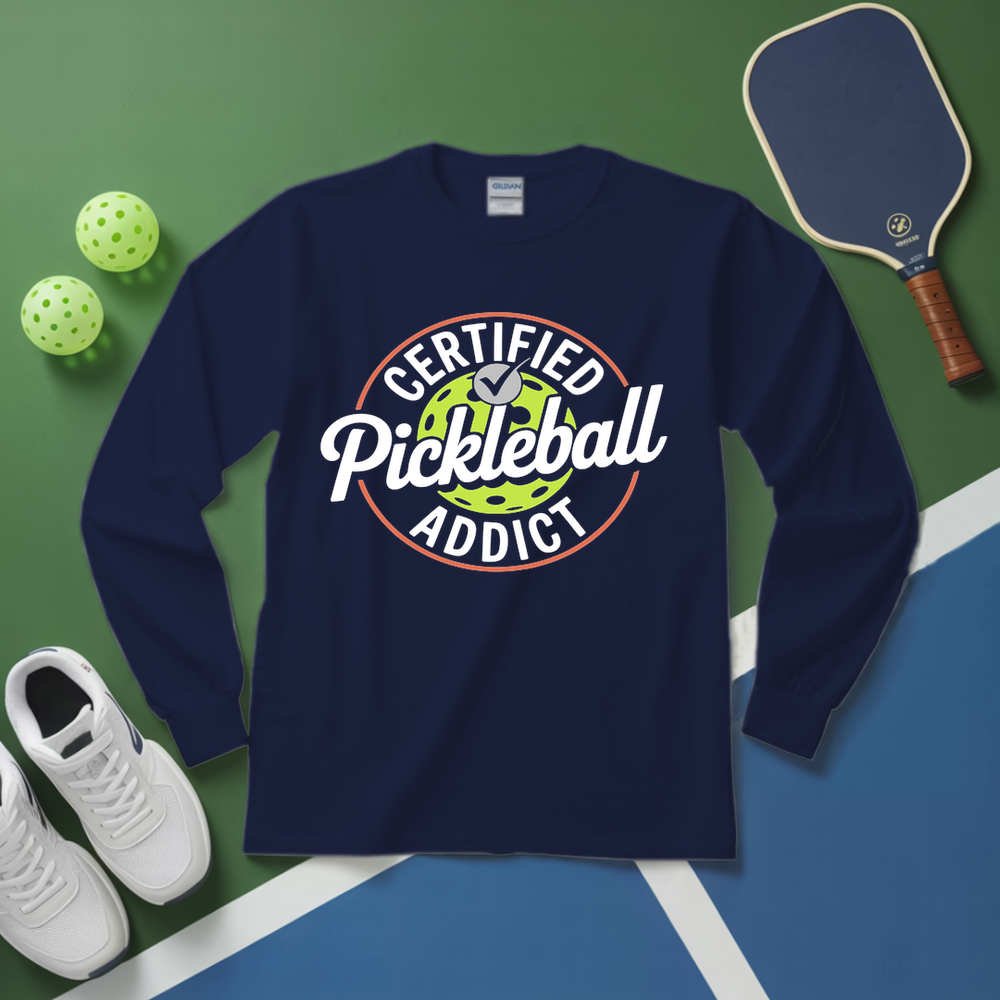 Navy blue sweatshirt with 'Certified Pickleball Addict' design on a green and blue surface with pickleball equipment.