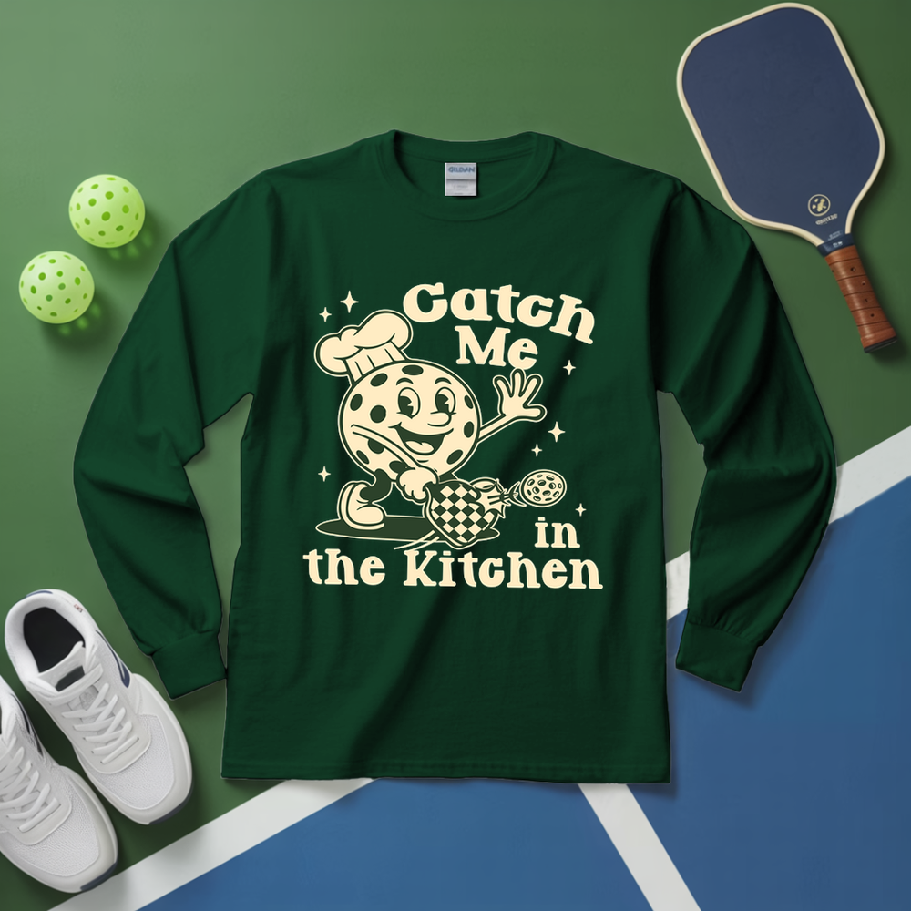 Green long-sleeve shirt with a pizza graphic and text on a green and blue surface with sports equipment.