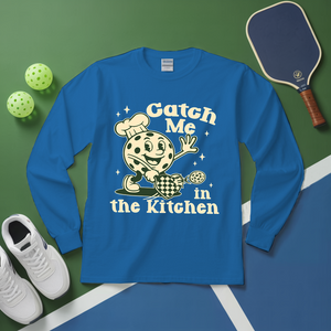 Blue long-sleeve shirt with a graphic design and text on a green and blue surface with sports equipment.