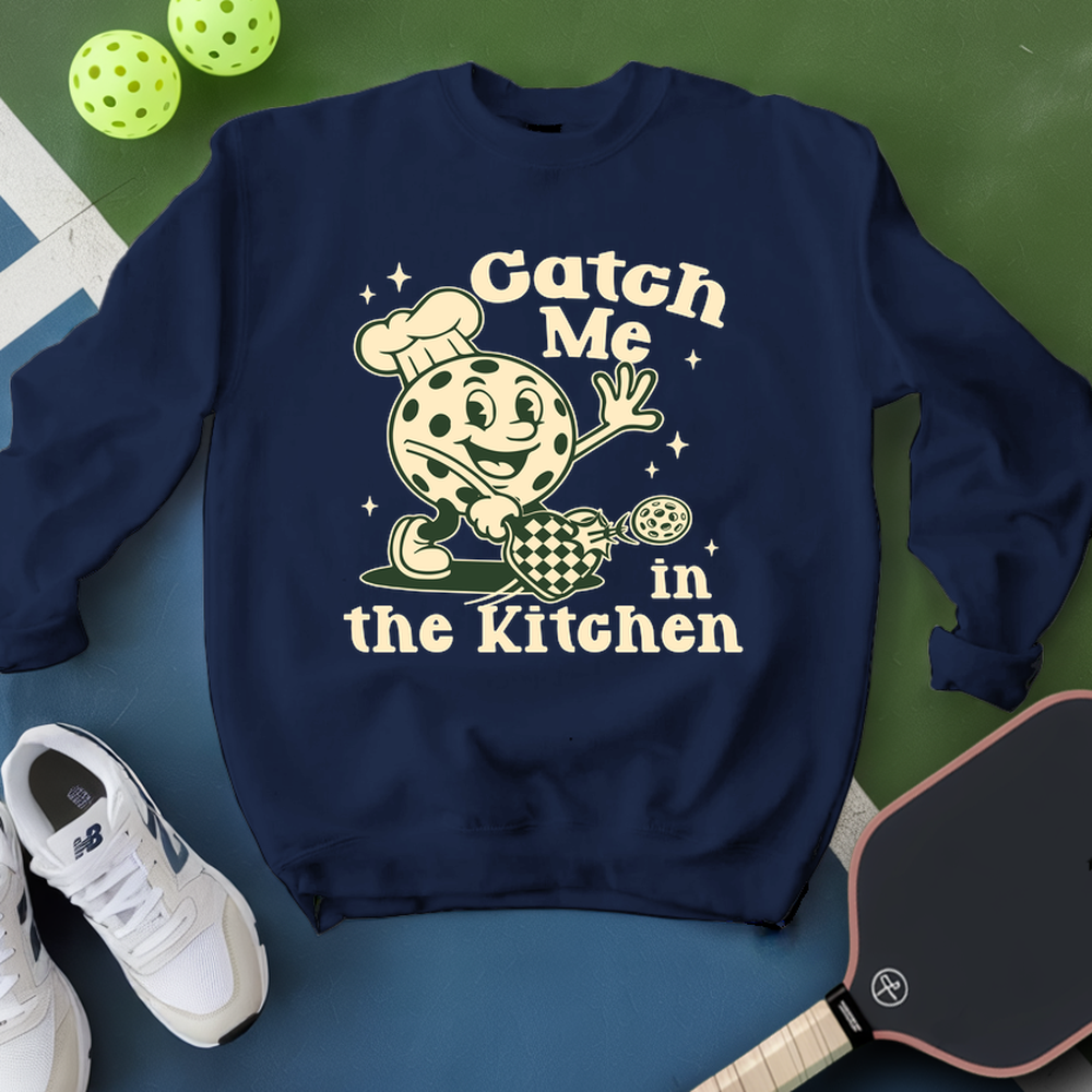 Navy blue sweatshirt with a graphic design and text, placed on a green and blue surface with sports equipment.
