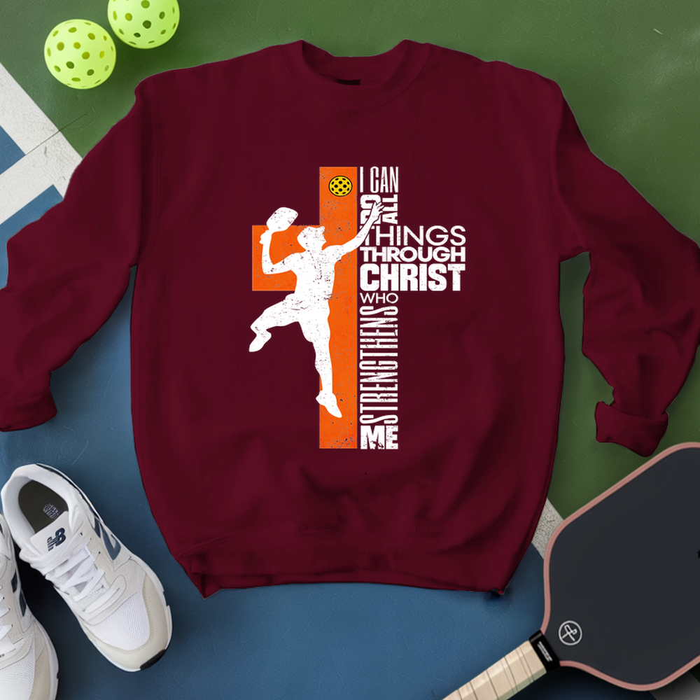 Maroon sweatshirt with sports-themed design and pickleball equipment on a green and blue background