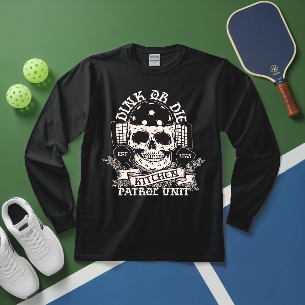 Black long-sleeve shirt with skull graphic and text on a green and blue surface with sports equipment.
