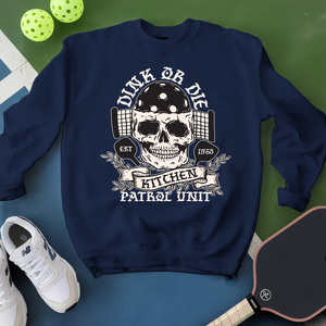 Navy blue sweatshirt with skull design and text, placed on a green and blue surface with sports equipment.