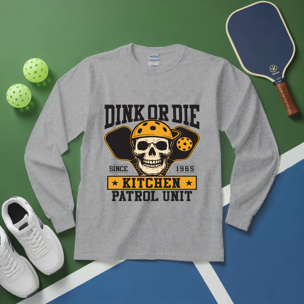 Gray long-sleeve shirt with skull graphic and text on a green and blue background with pickleball equipment.