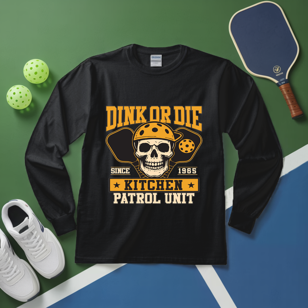 Black long-sleeve shirt with skull design and text on a green and blue surface with pickleball equipment.