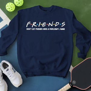 Navy blue sweatshirt with 'FRIENDS' text, white sneakers, and pickleball equipment on a green and blue surface.