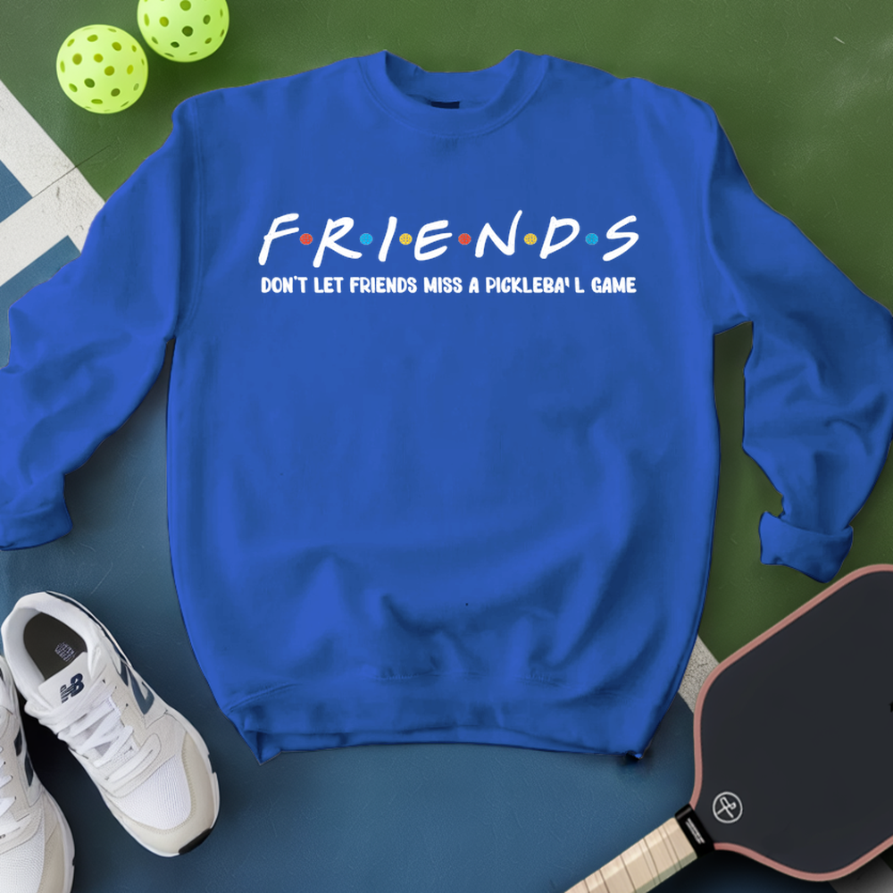 Blue sweatshirt with 'FRIENDS' text, white sneakers, and pickleball paddle on a green surface
