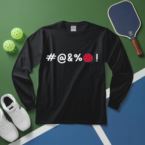 Black long-sleeve shirt with '#@&%' text, pickleball paddle, balls, and shoes on a green and blue surface.