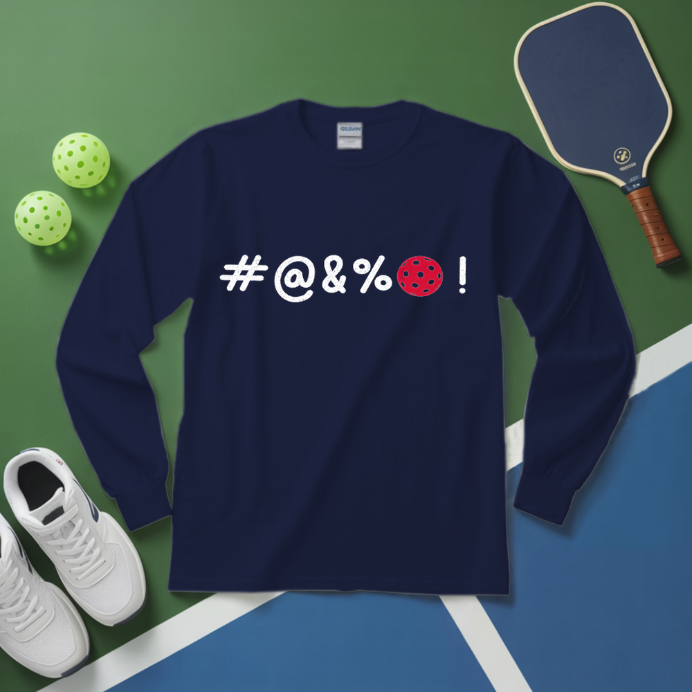 Navy blue long-sleeve shirt with '#@&%' text and pickleball ball design on a green and blue surface with sports equipment.