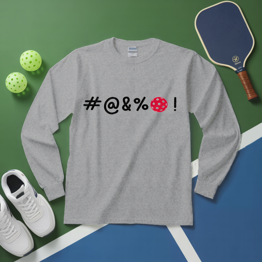 Gray long-sleeve shirt with censored text, white sneakers, pickleball balls, and paddle on a green and blue surface.