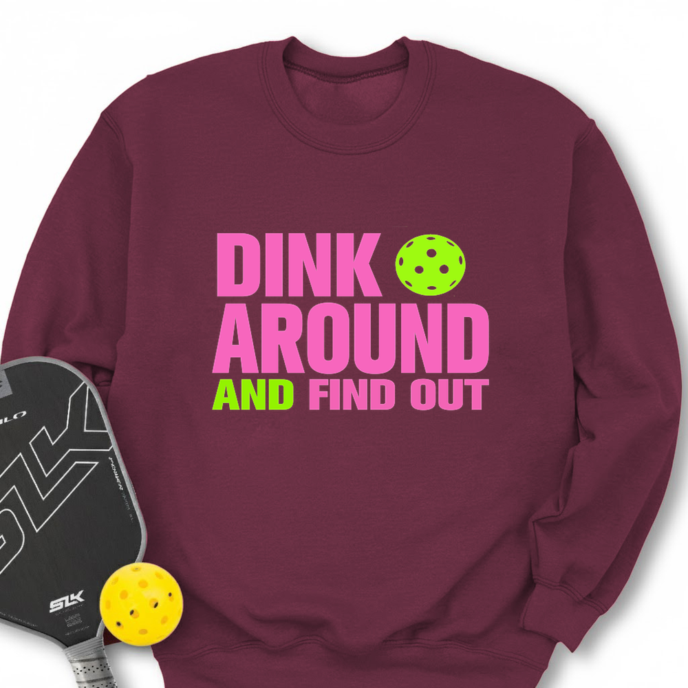 Maroon sweatshirt with 'Dink Around and Find Out' text and pickleball accessories on a white background