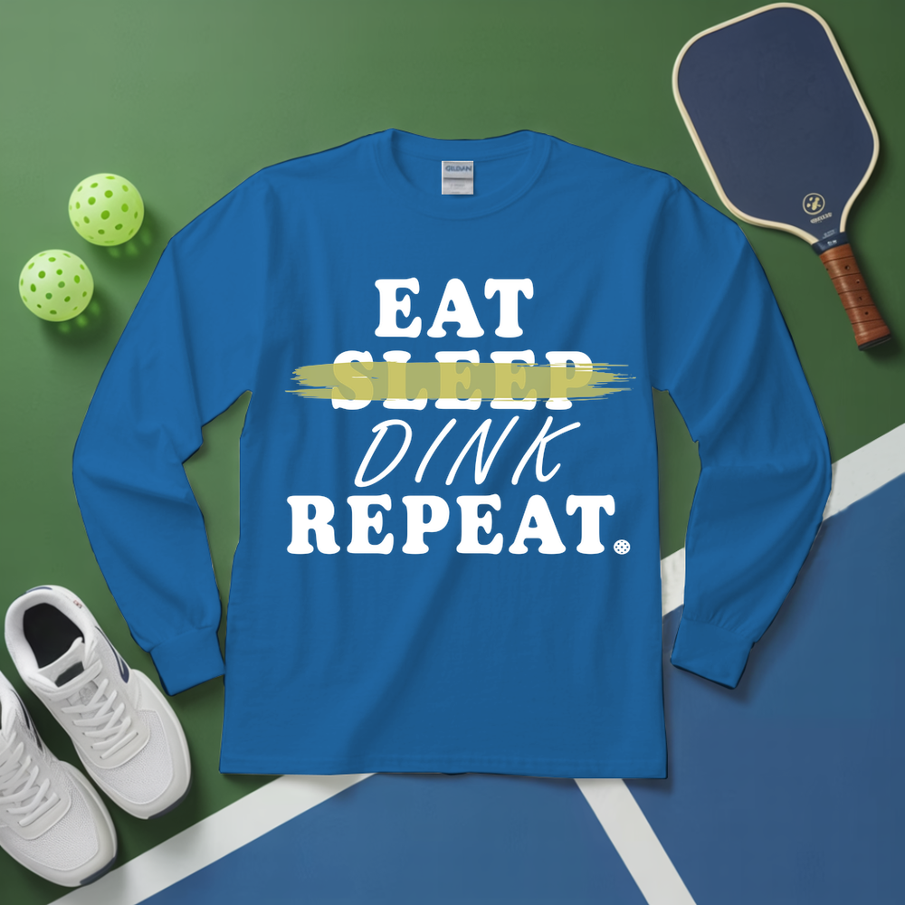 Blue long-sleeve shirt with 'Eat Sleep Dink Repeat' text on a green and blue sports court background.