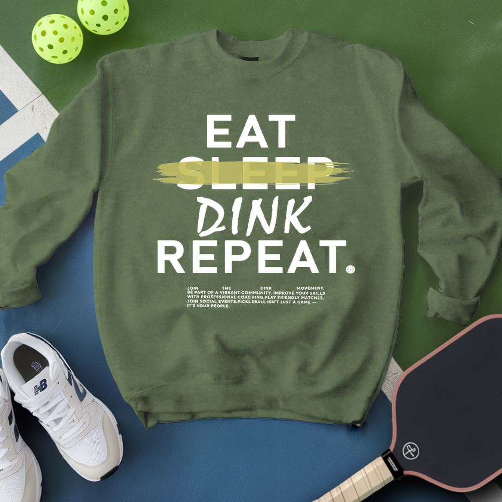 Green sweatshirt with 'Eat Sleep Dink Repeat' text, pickleball balls, paddle, and shoes on a green and blue background