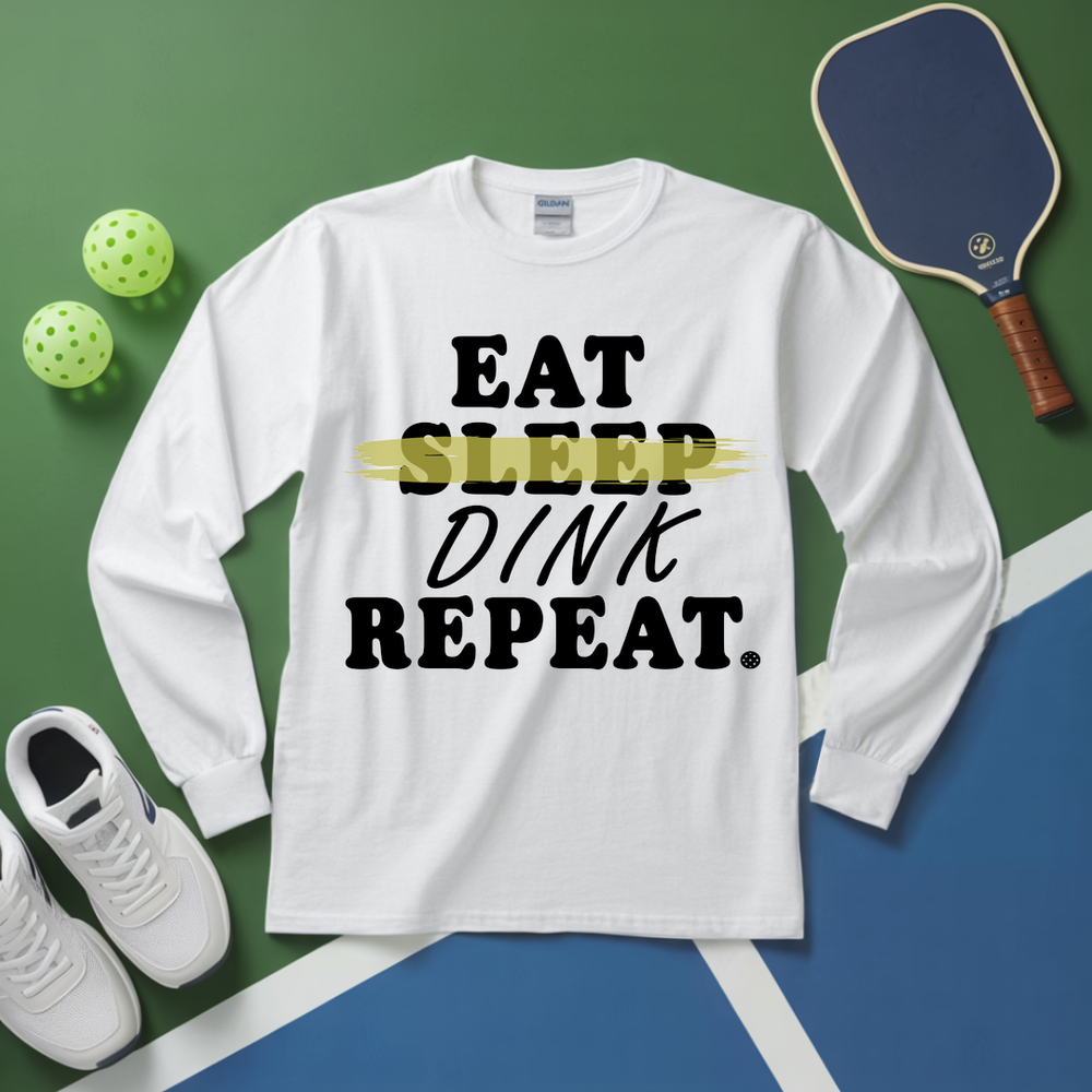 White long-sleeve shirt with 'EAT SLEEP DINK REPEAT' text, pickleball equipment on a green and blue background