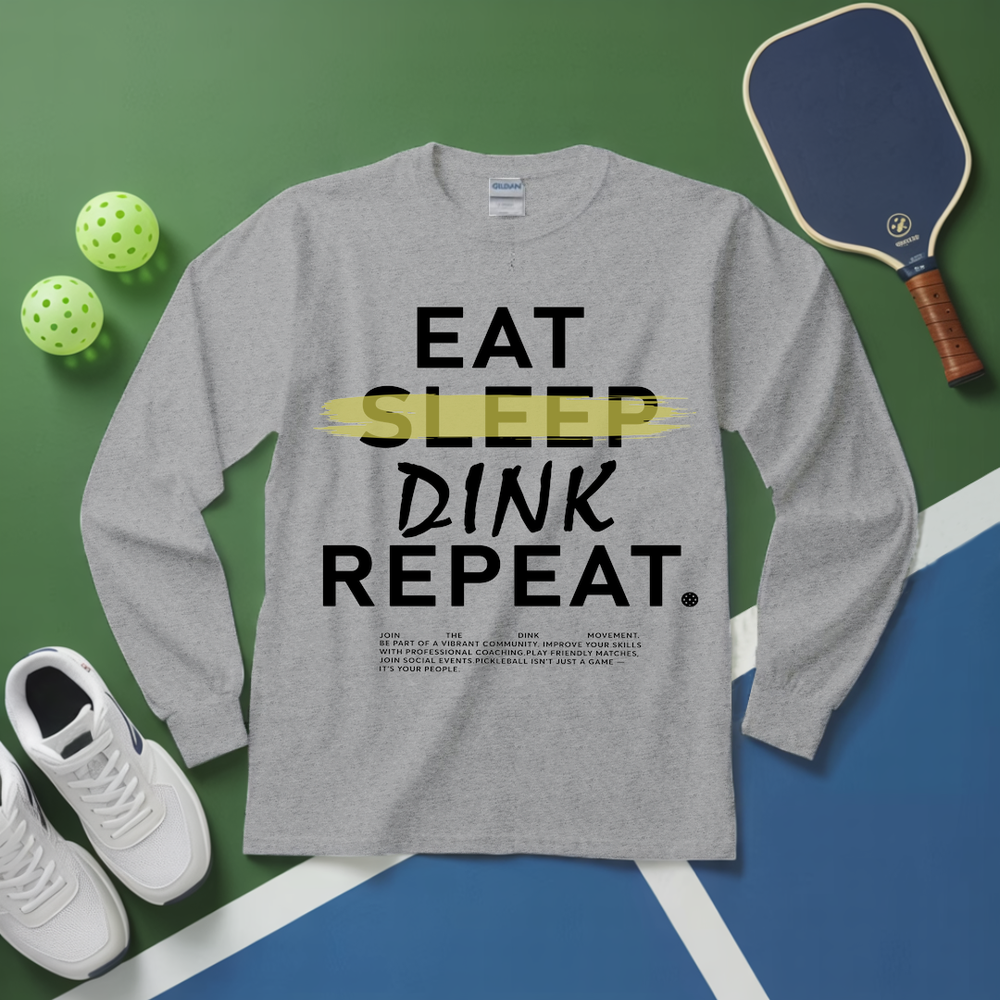 Gray long-sleeve shirt with 'EAT SLEEP DINK REPEAT' text, pickleball equipment on a green and blue background