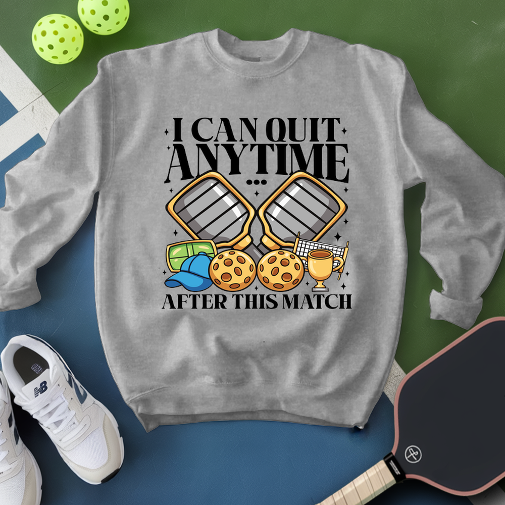 Gray sweatshirt with pickleball-themed design and text, surrounded by pickleballs and a paddle.