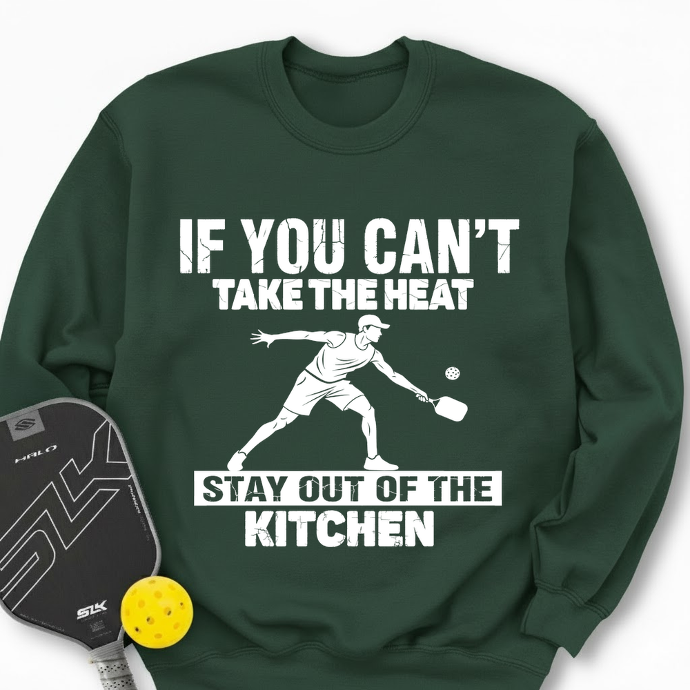 Green sweatshirt with pickleball graphic and text, accompanied by a paddle and ball on a white background.
