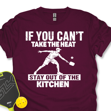 Maroon t-shirt with white text and pickleball player graphic, accompanied by a pickleball paddle and ball on a white background.