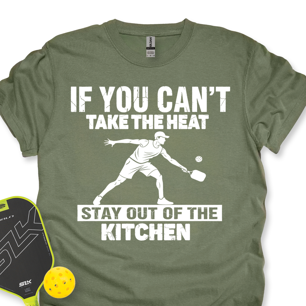 Green t-shirt with a graphic and text about pickleball, next to a pickleball paddle and ball on a white background.