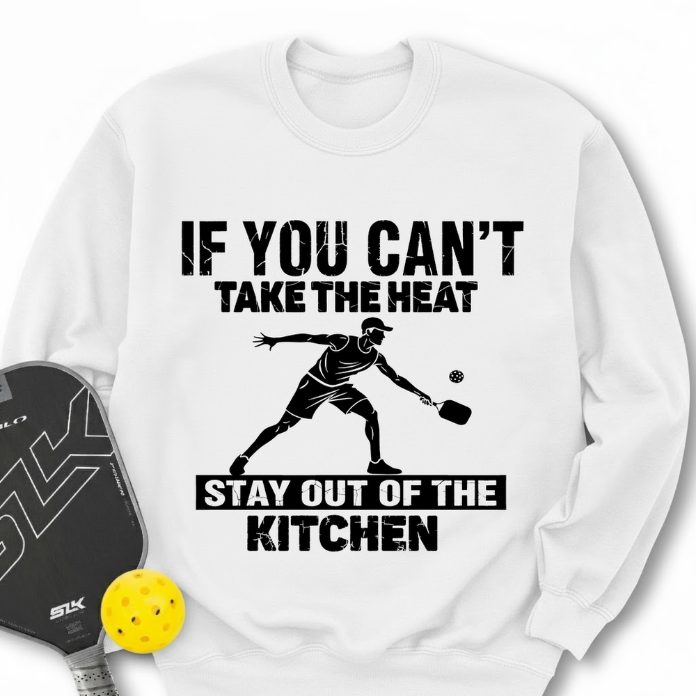 White sweatshirt with pickleball design and text, accompanied by a paddle and ball on a white background.