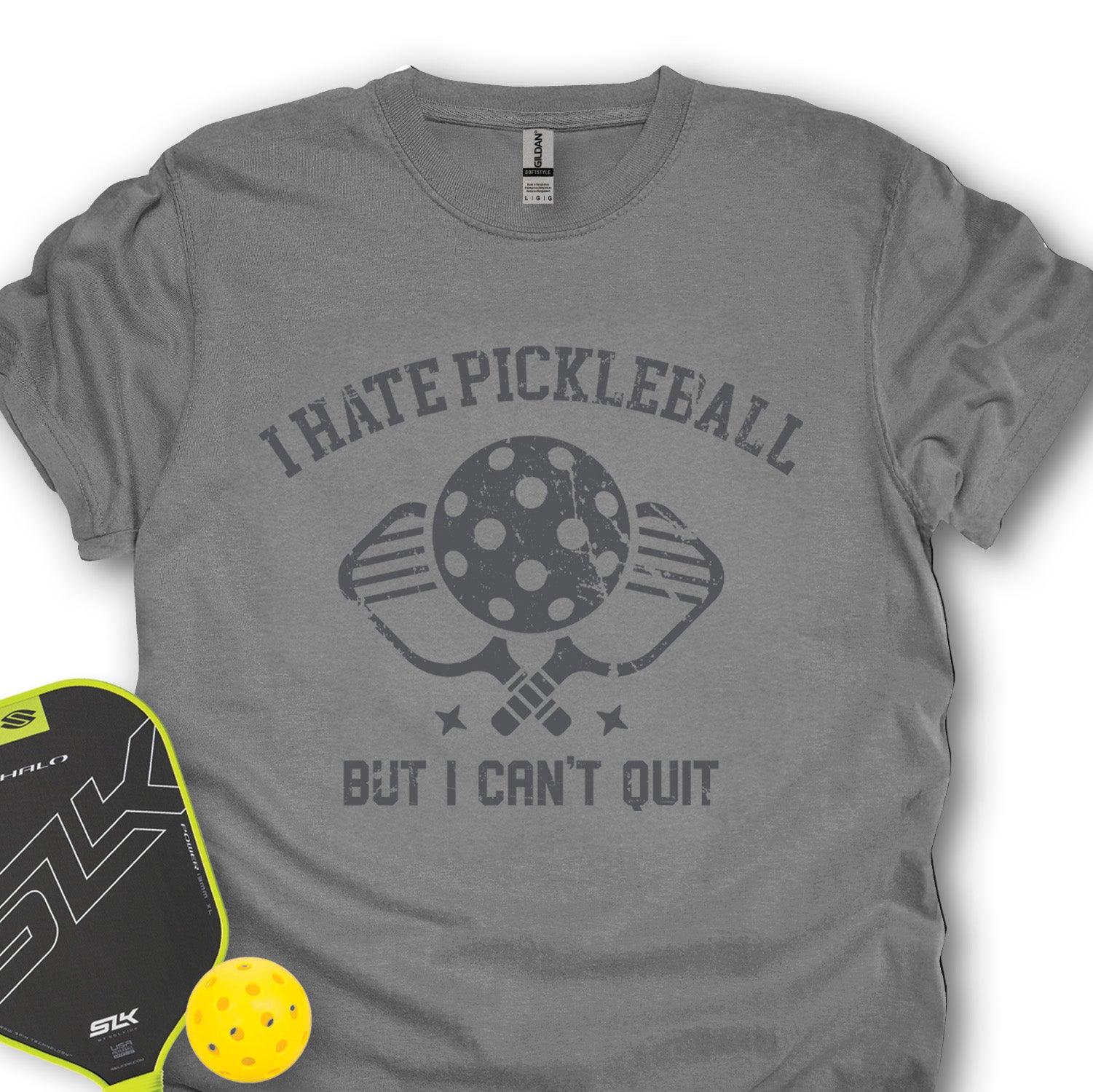 Gray t-shirt with 'I Hate Pickleball But I Can't Quit' text, pickleball paddle, and ball on a white background