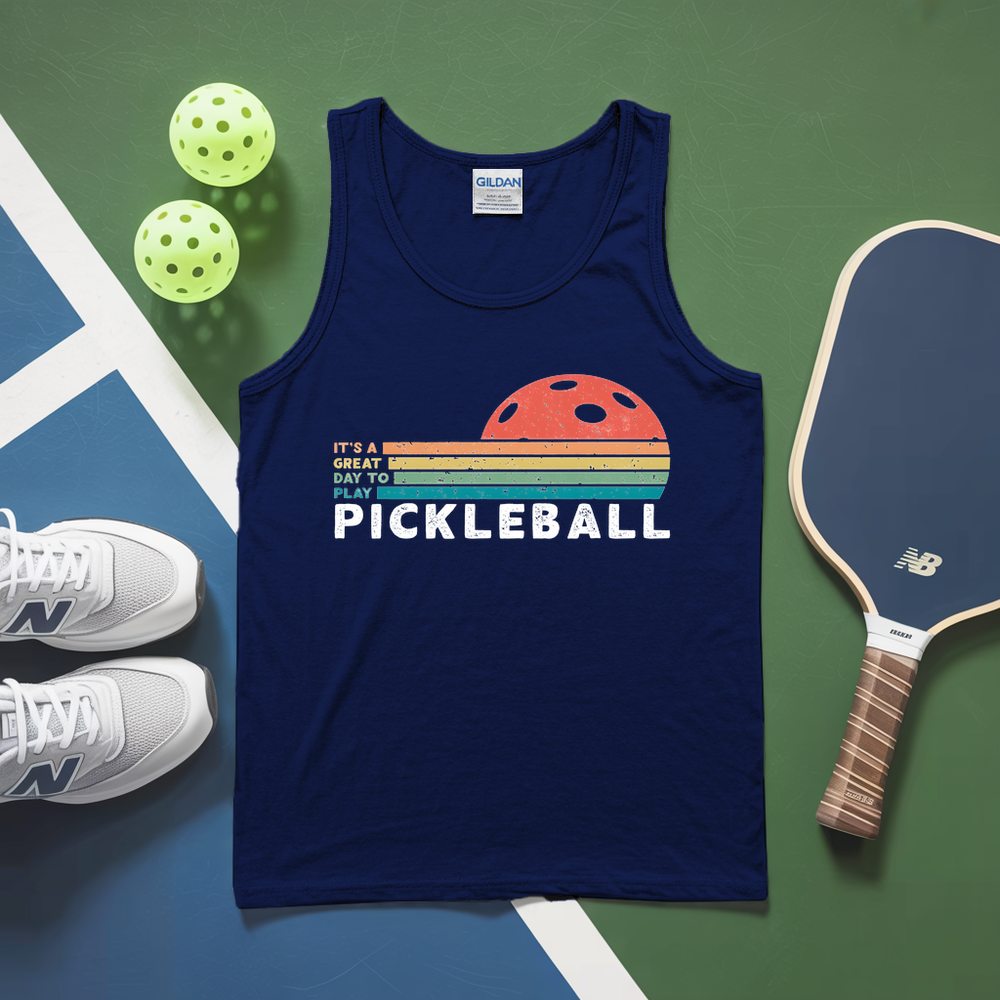 Blue tank top with pickleball design on a green and blue surface with pickleballs and a paddle.