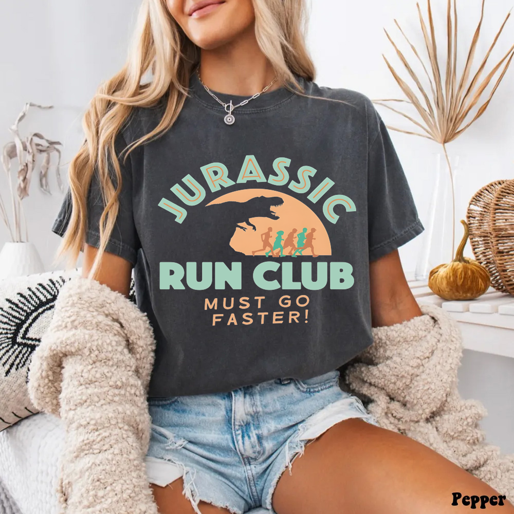 Person wearing a 'Jurassic Run Club Must Go Faster!' t-shirt in a casual setting.