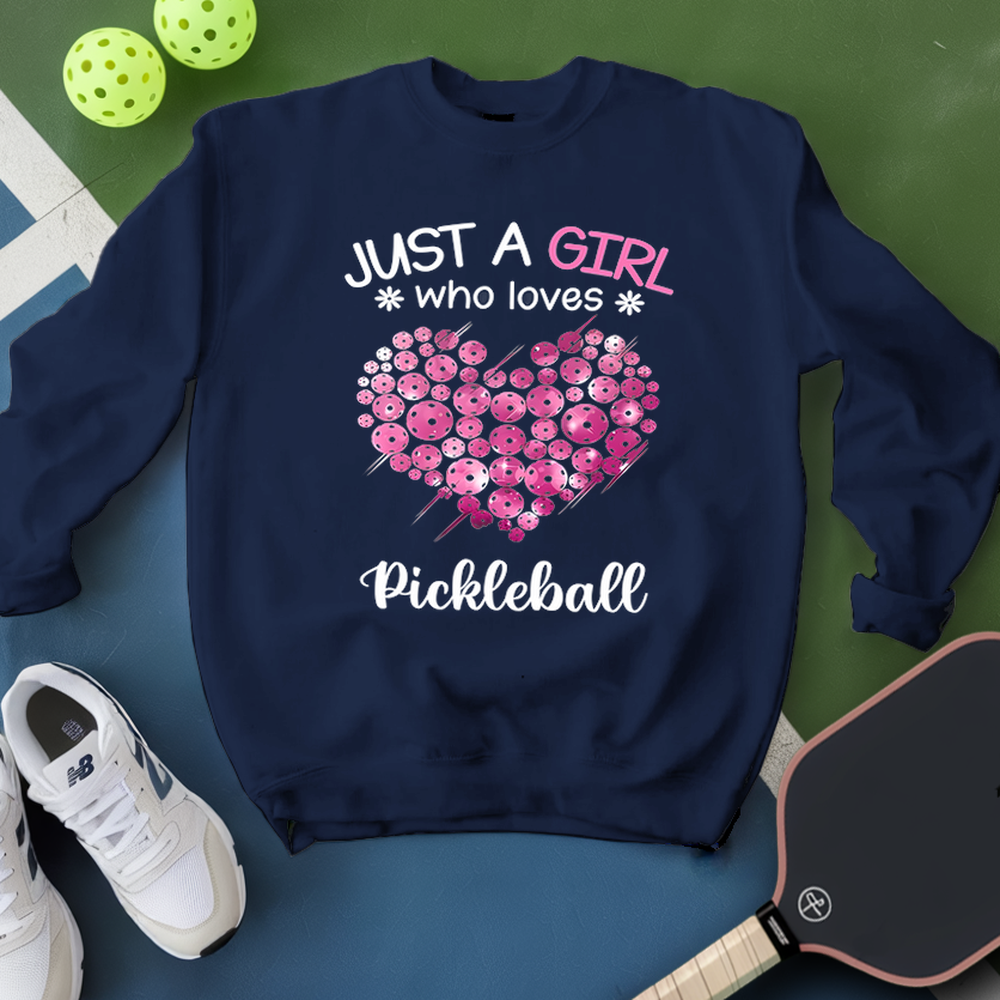 Navy blue sweatshirt with pink floral heart design and text on a green and blue background with pickleball equipment.