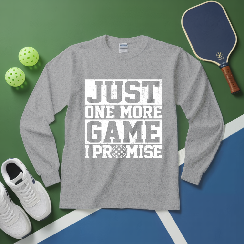 Gray long-sleeve shirt with 'Just One More Game I Promise' text, pickleball equipment on a green and blue background