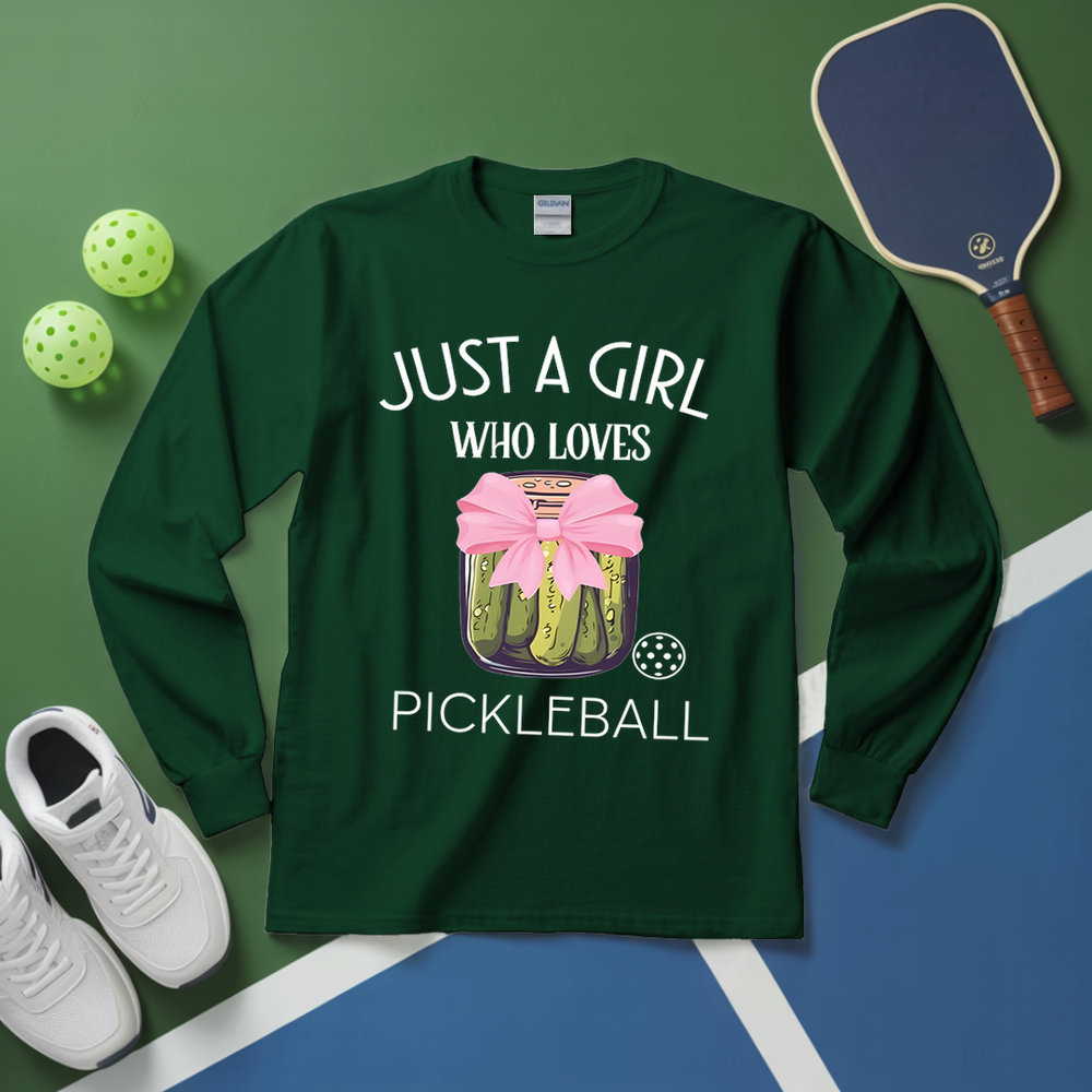 Green long-sleeve shirt with pickleball design and text on a green and blue surface with pickleball equipment.