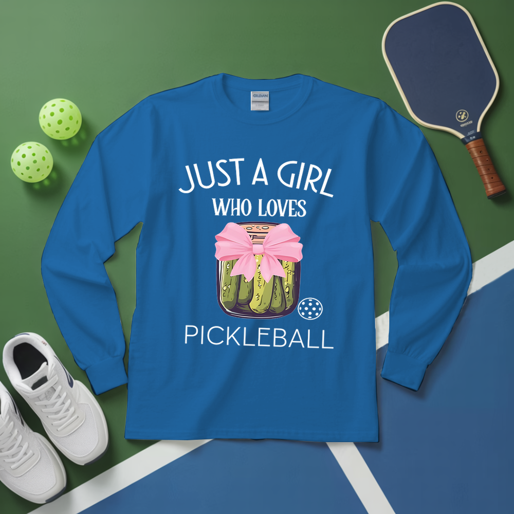 Blue long-sleeve shirt with pickleball design and text on a green and blue surface with pickleball equipment.