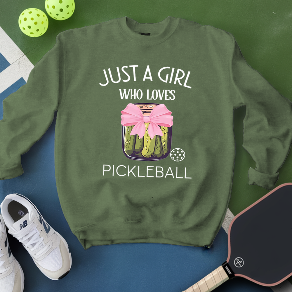 Green sweatshirt with pickleball design and text, surrounded by pickleballs and a paddle on a green and blue background.