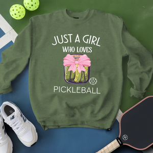 Green sweatshirt with pickleball design and text, surrounded by pickleballs and a paddle on a green and blue background.