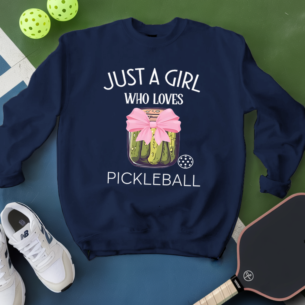 Navy blue sweatshirt with pickleball design and text, placed on a green and blue surface with pickleball equipment.