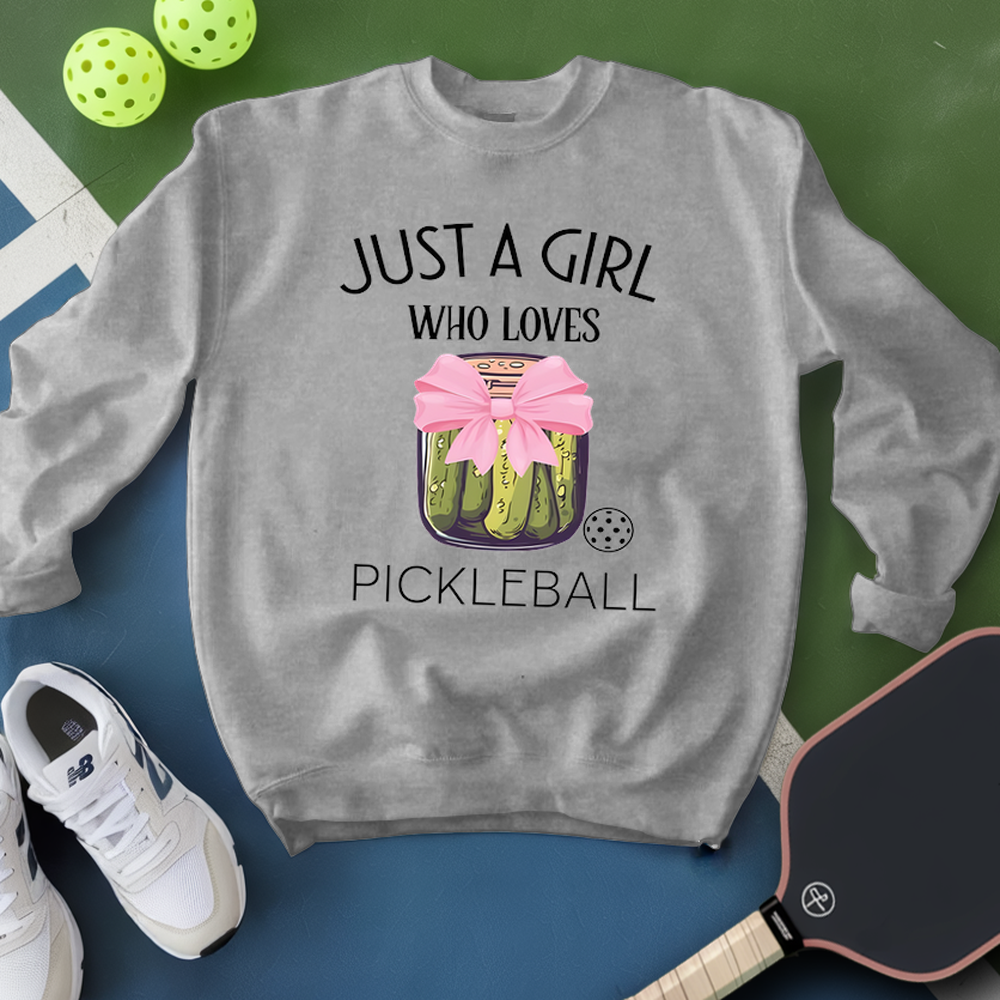 Gray sweatshirt with pickleball design and text, surrounded by pickleballs and a paddle on a green and blue background.